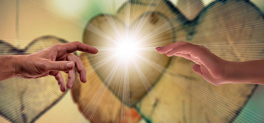 Két kéz ragyogó fénygömb felé nyúl, változás és spirituális újjászületés