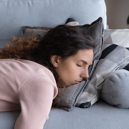 Nő pihen a kanapén, alacsony energia, feltöltődés szükségessége